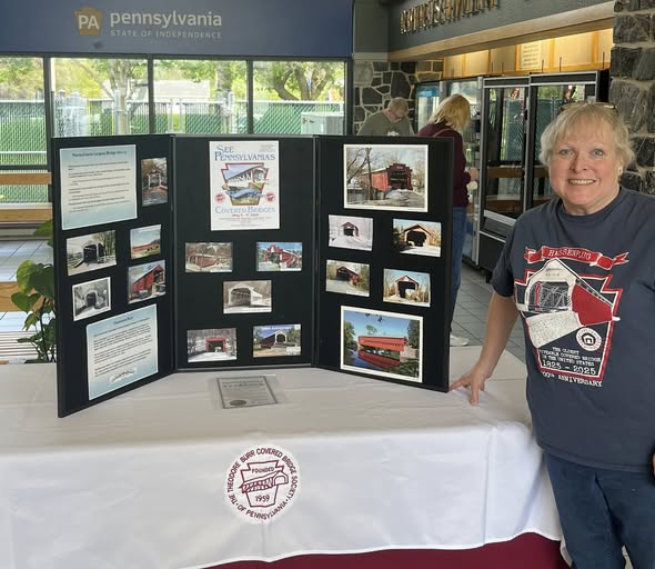 Pam Mailey with covered bridge display at a Welcome Center